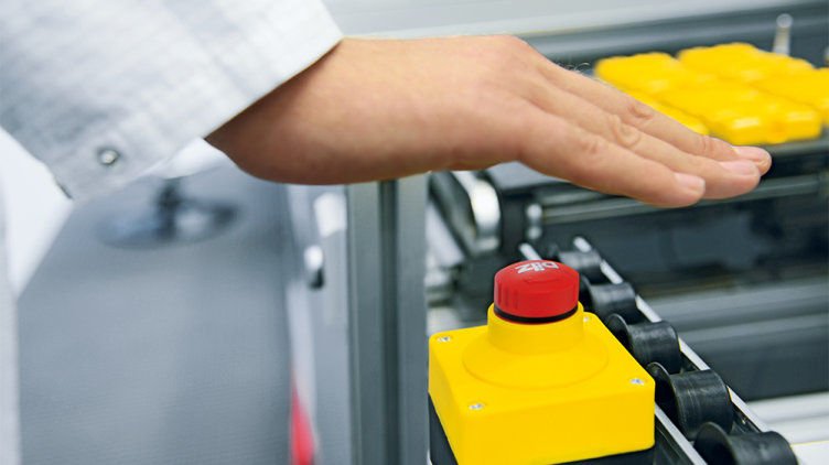 Operator pressing an emergency stop button on machine control equipment